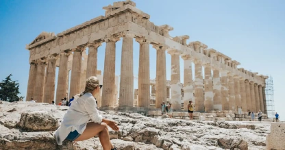 A woman unwinding as she gazes at the majestic Parthenon in Athens.