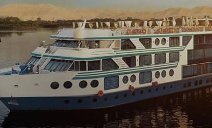 Nilkreuzfahrtschiff auf dem Nil im Abendlicht, im Hintergrund die Berge des Westufers