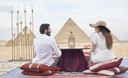 Tourists enjoying a traditional outdoor meal with the Pyramids of Giza in the background.