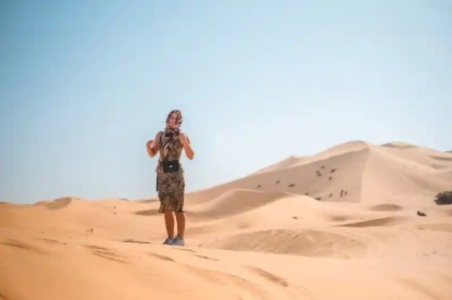 Una giovane donna cammina attraverso una duna di sabbia, Marrakech deserto agafay Una giovane donna cammina attraverso una duna di sabbia, Marrakech deserto agafay