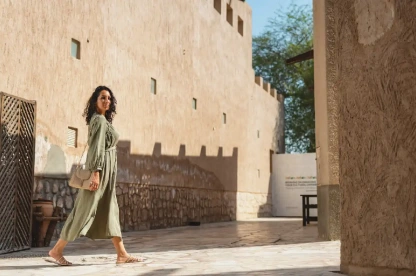 A Middle Eastern woman walks through a sunlit Al Fahidi courtyard in Dubai.