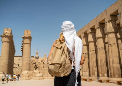 Traveller in a white headscarf standing before the columns of Luxor Temple on a Nile cruise shore excursion