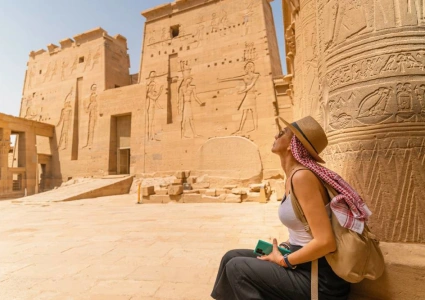Traveller admiring carved reliefs on the columns of Philae Temple in Aswan