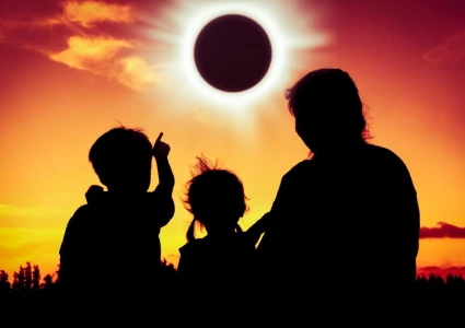 Family wearing certified solar viewers watching a total solar eclipse in a glowing sky