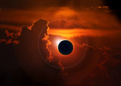 Total solar eclipse with the sun's corona breaking through red cloud