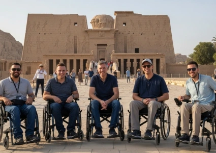   Five wheelchair users smile in front of the Temple of Horus at Edfu, framed by ancient carvings and clear skies—celebrating accessible tourism at a historic Egyptian site.