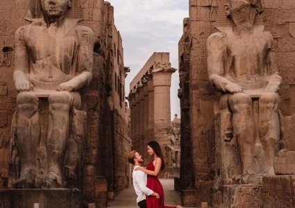 Couple posing romantically in front of Luxor Temple’s colossal seated statues and ancient stone architecture.
