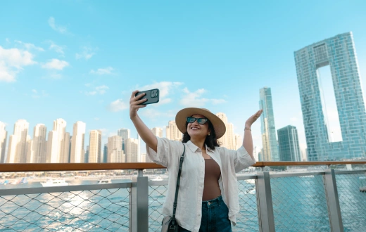 Young woman on the terrace of the hotel looking at Dubai Marina skyline with Address Beach resort and JBR buildings in background