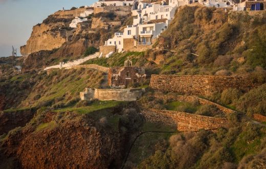 White city on a slope of a hill at sunset, Oia, Santorini, Greece