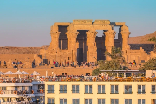 Der Doppeltempel von Kom Ombo im Abendlicht, davor ein Nilkreuzfahrtschiff