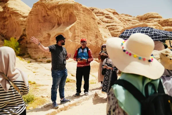 Reisegruppe mit Reiseleiter zwischen den Sandsteinfelsen von Petra in Jordanien