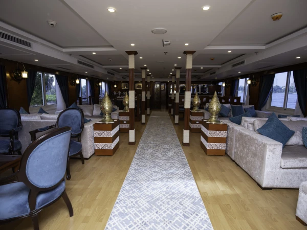 Lounge der Dahabeya Queen Isis mit Sofas, Sesseln und Panoramafenstern zum Nil