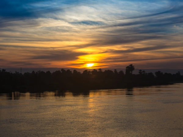 Sonnenuntergang über dem Nil mit Palmensilhouetten am Ufer