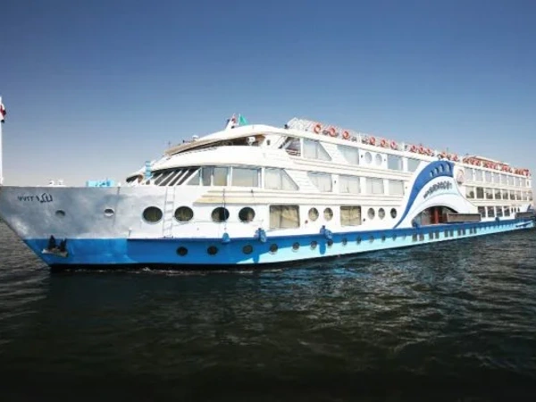 Nilkreuzfahrtschiff mit blau-weißem Rumpf auf dem Nil vor der Uferpromenade