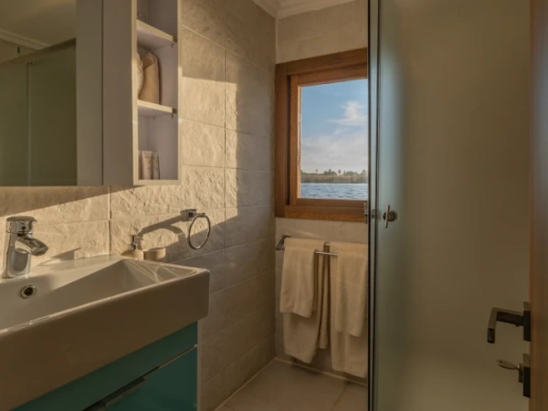 Badezimmer mit Fenster und Blick auf den Nil an Bord der Nuun & Nuut Dahabiyya