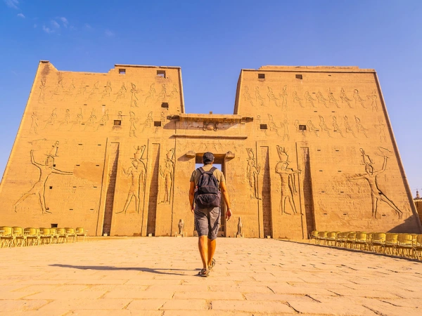 Mann mit Rucksack geht auf das Eingangstor des Edfu-Tempels in Ägypten zu