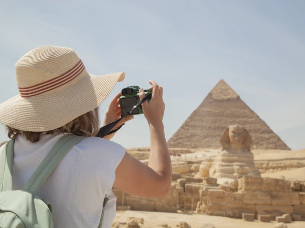 Person mit Strohhut fotografiert die Pyramiden und die Sphinx von Gizeh