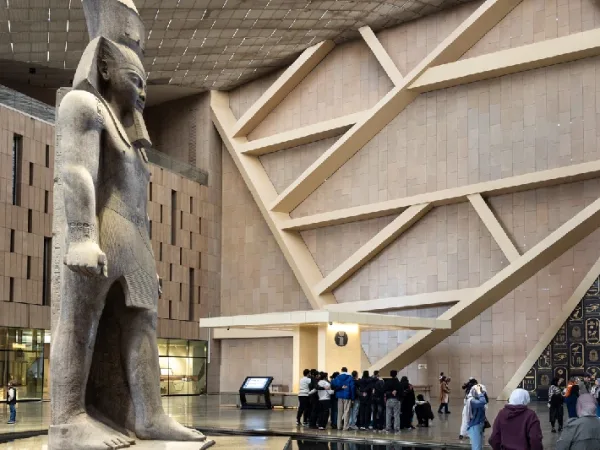 Große Pharaonenstatue in einer modernen Museumshalle mit Besuchern