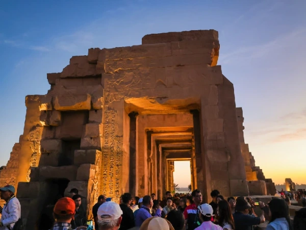Menschenmenge vor einem beleuchteten ägyptischen Tempel bei Sonnenuntergang