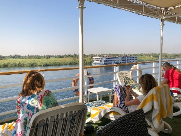 Gäste auf dem Sonnendeck eines Nilschiffs mit Blick auf den Nil