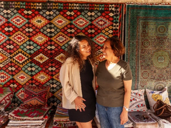 Zwei Reisende vor handgewebten Teppichen auf einem orientalischen Basar