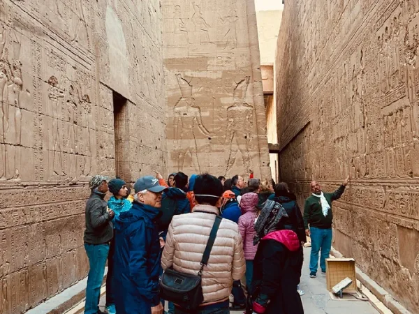 Reisegruppe mit Reiseleiter zwischen den Reliefwänden des Horus-Tempels in Edfu