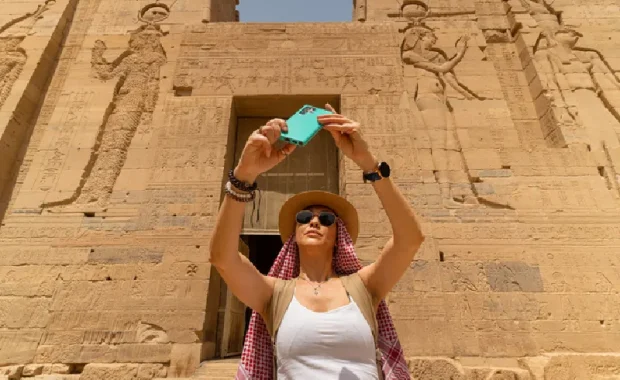 Mujer caminando por el Templo de Filae, también conocido como Templo de Isis, en Asuán, Egipto, mientras se toma un selfie, Viaje a Egipto Todo Incluido
