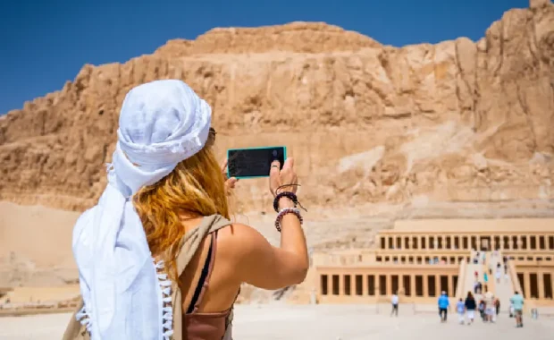 Mujer usando su smartphone para fotografiar el Templo de la Reina Hatshepsut, Viaje a Egipto Todo Incluido