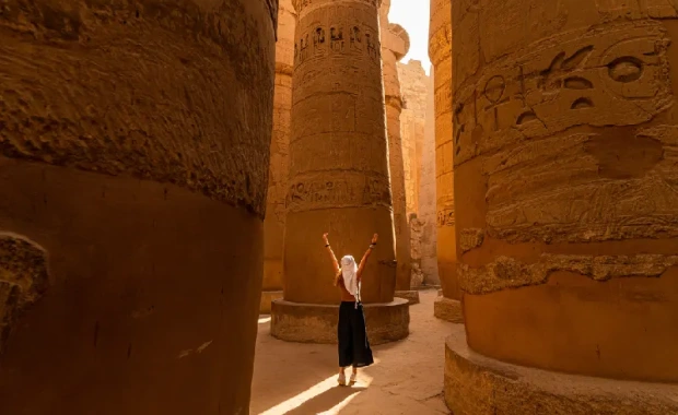Turista caminando entre las columnas de la Gran Sala Hipóstila del Templo de Karnak, Crucero por el Nilo de lujo