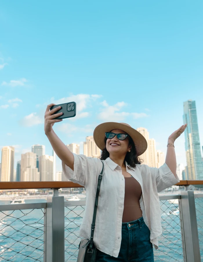 Young woman on the terrace of the hotel looking at Dubai Marina skyline with Address Beach resort and JBR buildings in background
