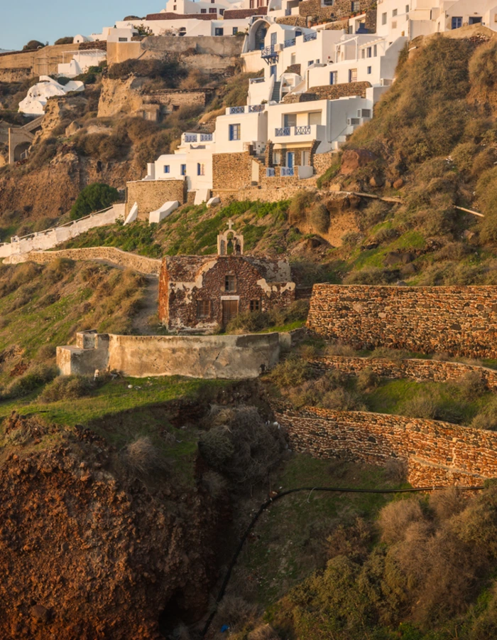 White city on a slope of a hill at sunset, Oia, Santorini, Greece