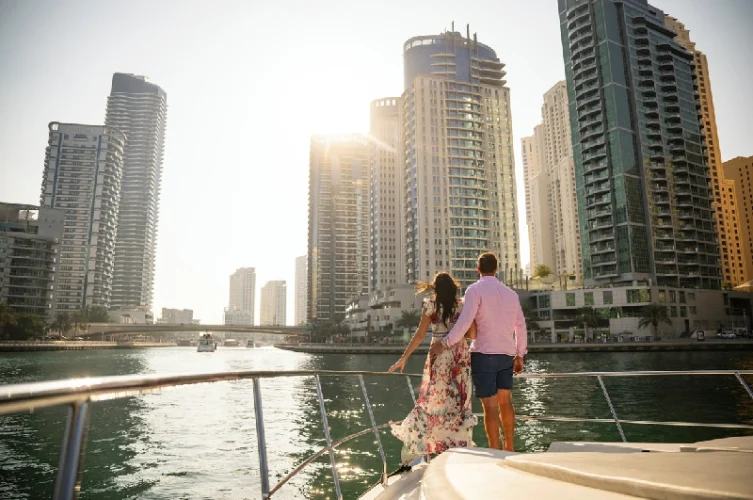 Un hombre y una mujer de vacaciones en los Emiratos Árabes Unidos, mirando hacia Dubai Marina al atardecer.