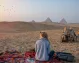 una mujer turista sentando enfrente a las Pirámides de Giza