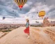 A tourist girl in Cappadocia amid floating hot air balloons.