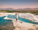 A woman in a white dress standing on the travertine terraces of Pamukkale.
