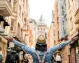 A girl stands with her arms raised in front of the Galata Tower in Istanbul.