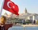 A boy enjoying a Bosphorus cruise with the Turkish flag waving beside him.