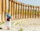 Traveler in a bright dress and hat admiring Jerash’s South Gate.