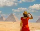 A tourist woman in a red dress gazing at the Great Giza Pyramids.