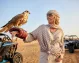 A traveler posing with a majestic falcon in the Dubai desert.