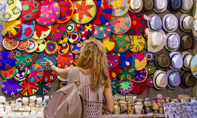 Mujeres frente a coloridas cestas y bolsos tejidos en un puesto del zoco de Aswan, Aswan Egipto