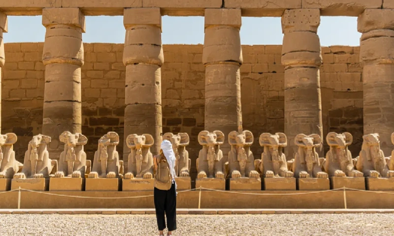 Turista caminando por el Templo de Karnak en Luxor, entre la Avenida de las Esfinges de la antigua Tebas, Luxor en Egipto