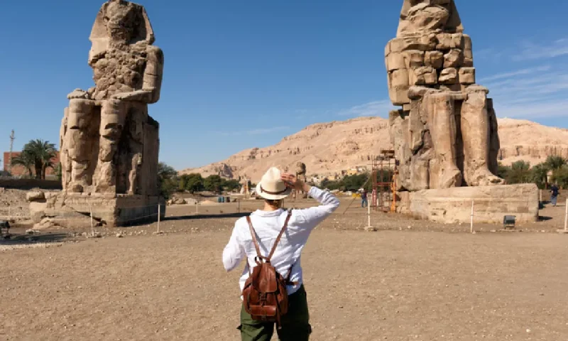 Turista interesada en la egiptología y la arqueología junto a los Colosos de Memnón en Luxor, Luxor en Egipto