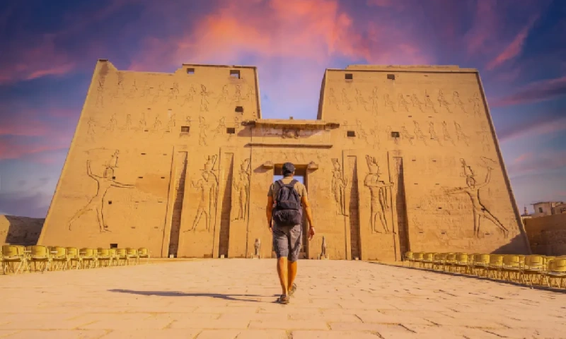 Una joven turista entrando en el Templo de Edfu, en la ciudad de Edfu, al atardecer, Templo de Edfu.