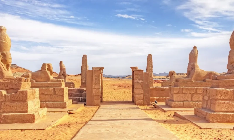 Entrada monumental del templo de kalabsha con estatuas de esfinges y columnas de piedra en un paisaje desértico de Egipto.