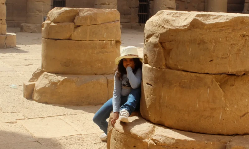 Niña aburrida sentada sobre los restos de una antigua columna en el Templo de Kalabsha.