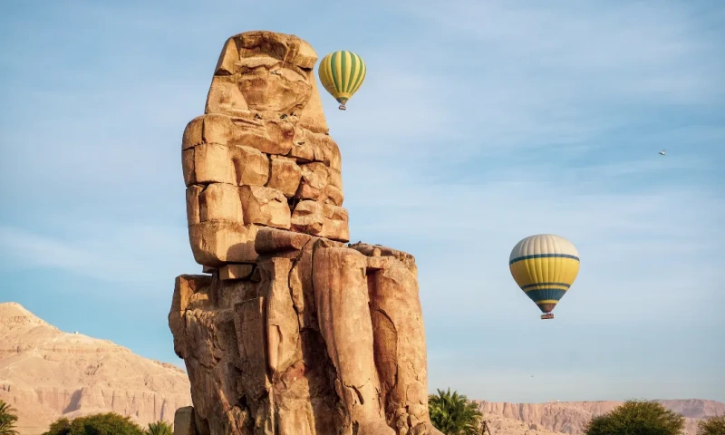 Colosos de Memnón en Luxor, Egipto, con globos aerostáticos flotando en el cielo azul sobre el valle del Nilo, Colosos de Memnón .