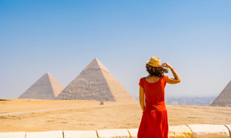 A young tourist in a red dress looking at the Pyramids of Giza,Visit Egypt