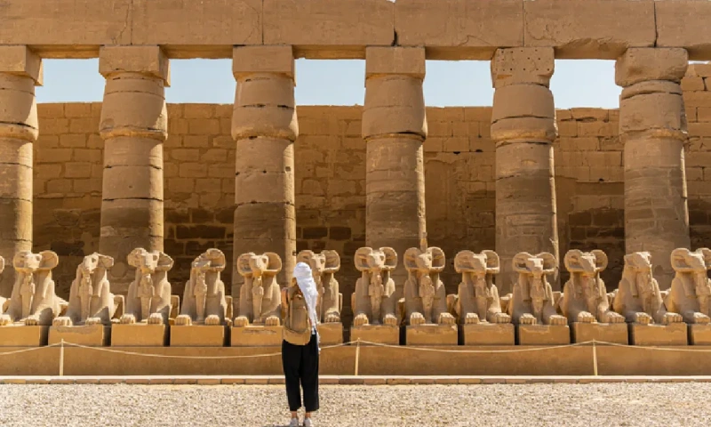 Turista caminando en el Templo de Karnak, en Luxor, entre la avenida de las esfinges de Tebas, Templo de Karnak.