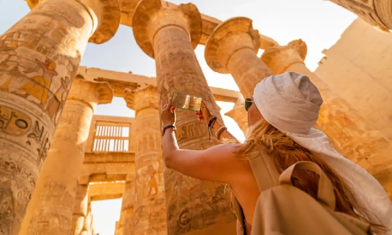 Turista caminando entre las columnas de la Gran Sala Hipóstila del Templo de Karnak mientras toma fotografías,Templo de Karnak.